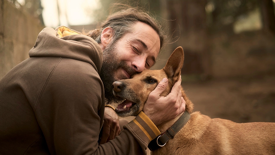 man knuffelende hond